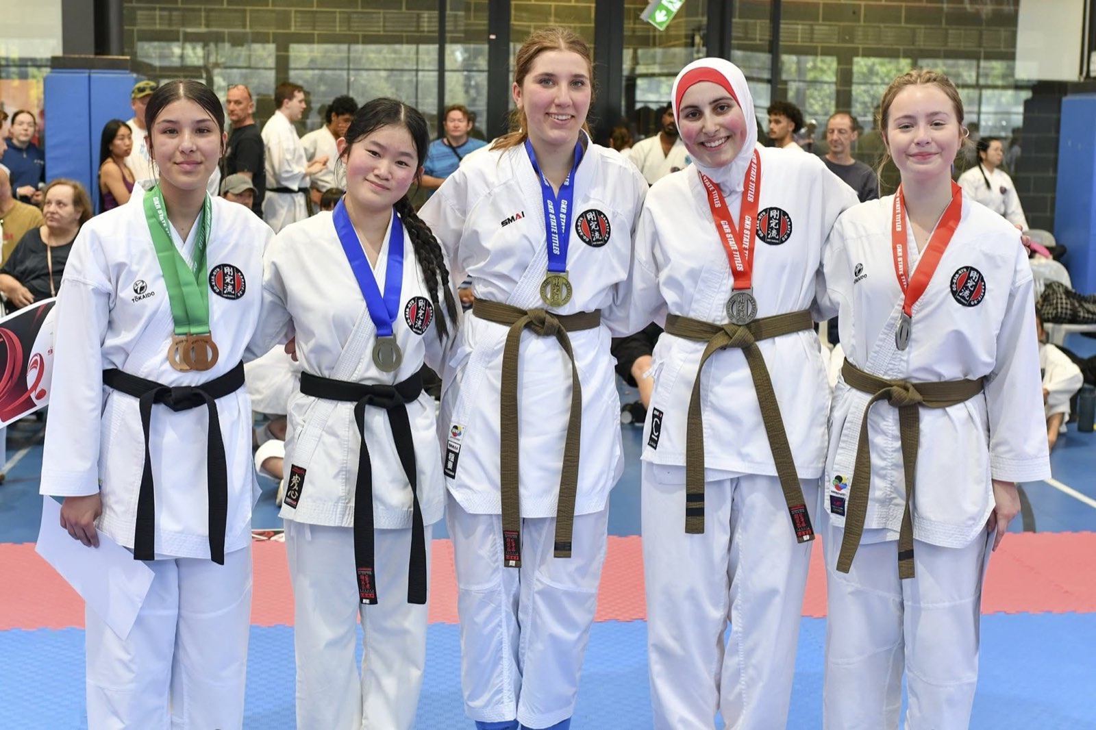 Five teenage competitors in their gis and belts, arm in arm, wearing their GKR State Titles medals.